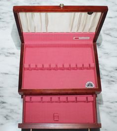 an open wooden box with pink linings on the bottom and inside, sitting on a marble surface