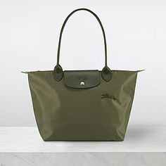 the le pliage green tote bag from longchamp, allows for it to be paired with all your favourite outfits thanks to its understated design. Fitted with a spacious interior to store items; its long handles mean you can wear it comfortably on your shoulder while its button flap and zipped closure ensures the safety of all your belongings. Green Longchamp, Longchamp Le Pliage Green, University Bag, Medium Purse