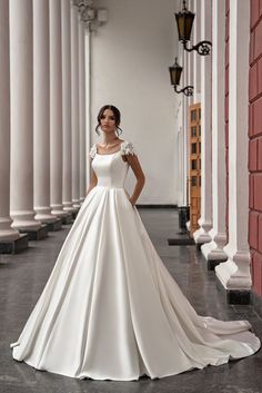 a woman in a white wedding dress standing on the floor next to columns and pillars