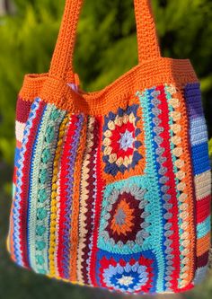 an orange crocheted bag hanging from a hook with trees in the back ground