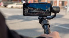 a person taking a photo with their cell phone on a tripod in the street