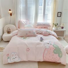 a bed with pink comforters and pillows in a room next to a window,