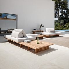 a living room with white couches and coffee table in front of a swimming pool