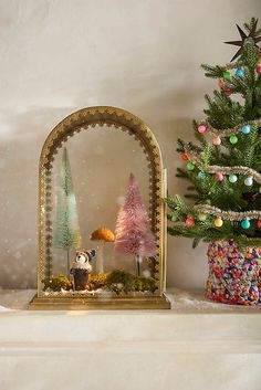 a small christmas tree in front of a mirror with ornaments on it and a fake snowman