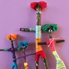 three different colored sticks with yarn on them and one is made to look like people