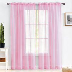 a pink curtain hanging on the side of a window next to a potted plant