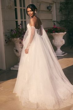 a woman in a white wedding dress standing on a patio with her back to the camera