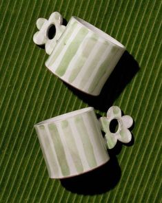 two green and white striped cups with flowers on them