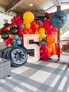 the number five is surrounded by balloons and race cars