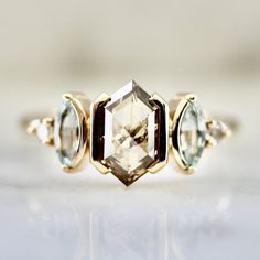 three different colored stones in a yellow gold ring