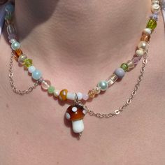 a woman wearing a multicolored necklace with an acorn and shell charm on it