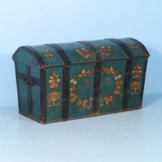 an old wooden chest with floral designs on it's sides and handles, sitting on a white surface