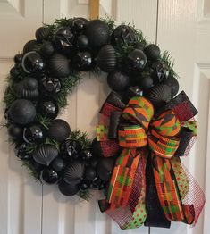 a wreath is hanging on the door with black balls and green grass in front of it