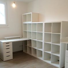 an empty room with white shelving and drawers