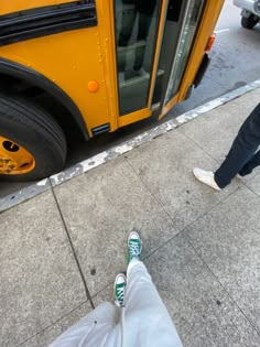 a person standing on the sidewalk next to a yellow school bus