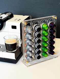 an espresso machine and cup of coffee on a white table with a black wall