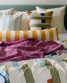 a bed with colorful pillows and blankets on it