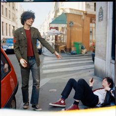 two young men standing next to each other on the street