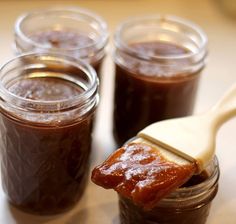 three jars filled with jam and a wooden spoon