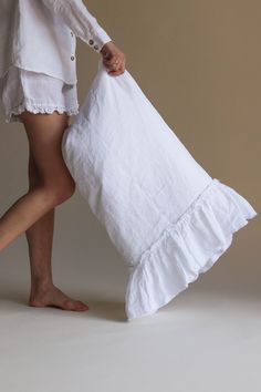 a woman in white shirt and shorts holding a white bag with ruffles on it