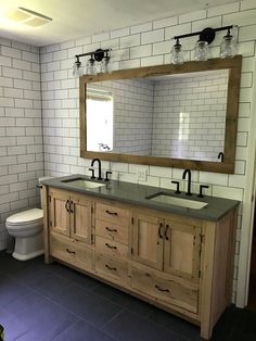 a bathroom with two sinks, a toilet and a large mirror over the sink in it