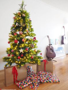 a christmas tree with presents under it and a guitar on the floor next to it