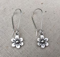 These are just so sweet and cute!  Little daisy dangle earrings.  Perfect addition to any outfit and sure to brighten your day!Made from allergy free plated silver.  The flowers measure 1/2” long by 3/8” wide and hang from 1” kidney style ear wires that lock and latch.  Overall drop length is 1 1/2”.  Thanks for stopping by!  Please take a moment and visit the rest of my Etsy shop.  I have many more unique jewelry designs to choose from!🌸 Tiger Flower Jewelry 🌸  🌸 Inspired by Nature 🌸 Whimsical Spring Flower Earrings With Ear Wire, Whimsical Adjustable Flower Charm Earrings, Cute Adjustable Flower Earrings For Spring, Cute Spring Earrings With Ear Wire, Everyday Dangle Earrings With Flower Charm, Cute Flower Shaped Hypoallergenic Earrings, Cute Hypoallergenic Flower-shaped Earrings, Cute Flower Charm Earrings For Everyday, Cute Nickel-free Flower Shaped Earrings