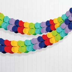 two pieces of paper are arranged in the shape of a rainbow streamer on a white wall