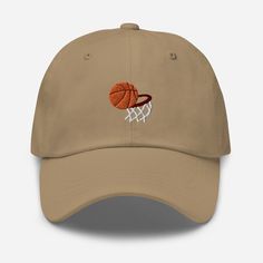 Elevate your sports style with the Basketball Embroidered Dad Hat, where athletic design meets comfort and versatility. 🏀 🧵 Product Details: Material: Crafted from 100% cotton twill, ensuring a soft and comfortable feel. * Design: Showcases a bold basketball embroidered motif, expressing your love for the game and athletic spirit. * Style: Features an unstructured, 6-panel, low-profile design, offering a laid-back and sporty aesthetic. * Ventilation: Designed with 6 embroidered eyelets to prov Collegiate Cotton Trucker Hat With Curved Bill, Cotton Visor Baseball Cap With Letter Embroidery, Cotton Baseball Cap With Letter Embroidery, Breathable Cotton Cap, Collegiate Cotton Dad Hat With Curved Brim, Breathable Cotton Trucker Hat For Sports, Cotton College Hats For Baseball Season, Cotton Trucker Hat With Visor For Sports, Cotton Snapback Hats For College