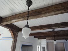 a light fixture hanging from the ceiling in a room with white walls and wood beams