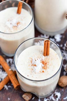 two glasses filled with milk and cinnamon sticks