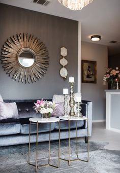 a living room with two tables and a couch in front of a mirror on the wall