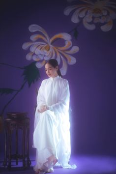 a woman in white sitting on a stool