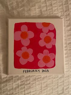 a red and pink square with flowers painted on the bottom is sitting on a white sheet