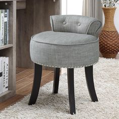 a grey chair sitting on top of a white rug in front of a book shelf