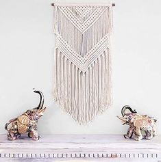 two elephants standing next to each other in front of a macrame wall hanging