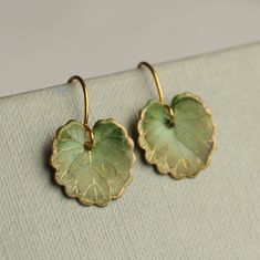 These olive green leaf earrings are brass charms with some amazing detail, which have been carefully treated, painted and varnished to bring out beautiful tones and depth of colour and to show the incredible veining and other details of the metal.  These are coloured a beautiful, delicate and multi toned olive green colour.   They are designed to be reminiscent of the beautiful, softly coloured lily pads found in Art Nouveau paintings. They are handmade in our Edinburgh studio and no two pairs are quite the same!  Our Leaf Earrings are available in two finishes: soft matte or a shiny glass appearance. The colour and level of detail on the earrings are exactly the same regardless of which you choose.  We've included an image for a better idea.   Each leaf is 15mm long. We offer these leaf e Green Leaf Earrings, Nickel-free Leaf-shaped Brass Jewelry, Handmade Delicate Green Jewelry, Delicate Handmade Green Jewelry, Green Brass Earrings Nature-inspired, Leaf-shaped Brass Earrings For Gift, Leaf-shaped Brass Earrings As Gift, Green Leaf-shaped Earrings For Pierced Ears, Nickel-free Green Leaf-shaped Jewelry