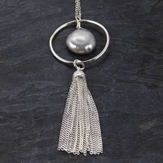 Our sterling silver and freshwater pearl tassel necklace is a trendy yet delicate piece of jewelry. This would make a great gift for the girl that loves subtle statement necklaces that are easy to wear. Details The necklace is 32.5 inches long The tassel and circle component are a little 2.5 inches long. Since the necklace is so long, there is no clasp making it easy to take on and off. The freshwater pearl is an iridescent gray with hints of purple and green hues. Please note that each pearl ma Party Necklaces With Tassels And Dangle Shape, Party Dangle Necklaces With Tassels, Party Tassel Dangle Necklaces, Chic Silver Jewelry With Tassels, Chic Silver Jewelry With Fringe, Chic Silver Fringe Jewelry, Chic Long Tassel Necklaces, Bohemian Lariat Necklace With Tassels For Gifts, Bohemian Lariat Necklace With Tassels As Gift