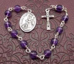 "Amethyst Guardian Angel Single Decade Rosary This is a beautiful handmade light purple Amethyst single decade rosary bead set. It is made with a detailed small Crucifix at one end and a lovely Guardian Angel at the other. HAIL MARY ~6mm Amethyst beads. OUR FATHER ~6mm Amethyst bead hugged by antique silver colour detailed bead caps. Deep purple Amethyst is considered to be a protective stone which soothes & balances. It is thought to purify the aura of negative energy.  Purple Amethyst is considered to be a protective stone which soothes & balances; it is thought to purify the aura of negative energy. The small detailed Crucifix is set onto one end of the rosary and measures approximately 1\" x 1/2\" (~24mm x 12mm). The beautiful Guardian Angel medal measures around 1\" x 5/8\" (25mm x 15 Pocket Rosary, Decade Rosary, Hail Mary, Handmade Lighting, Bead Set, Silver Colour, Rosary Beads, Amethyst Beads, Guardian Angel