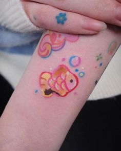 a person with a colorful tattoo on their arm holding onto her wrist and the other hand