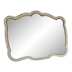 a mirror that is sitting on top of a white wall mounted shelf with gold trimmings