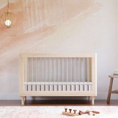 a baby crib in front of a wall with a painting on it and toys scattered around