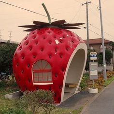 a large strawberry shaped building on the side of a road