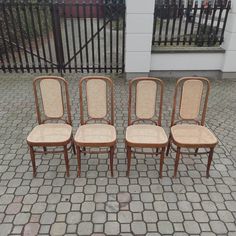 four chairs sitting on top of a brick floor next to a fenced in area