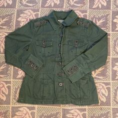 Features Pockets On The Waist, Button Up Pockets On The Chest, And Button Up Cuffs. Has Camo Lining On The Inside Of Jacket. In Great Condition. Never Worn, No Tears, But Has Small White Spots From Steamer On The Back And On The Back Of One Sleeve As Pictured. Tag Says Size Medium, But Fits Like Size Small. Measurements: 27” Inches In Length, 38” Chest, 42” Waist When Buttoned, And 22” Sleeves. Spring Military Outerwear With Buttoned Pockets, Military Style Long Sleeve Outerwear With Button Closure, Military Style Outerwear With Button Closure, Fall Military Utility Jacket With Button Closure, Fall Military Utility Jacket, Fall Military Style Utility Jacket With Button Closure, Fall Utility Blazer With Buttons, Green Utility Jacket With Button Closure For Fall, Cotton Button-up Outerwear With Double Button Closure