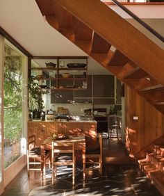 an open kitchen and dining area with stairs leading up to the upper floor, along with wooden furniture