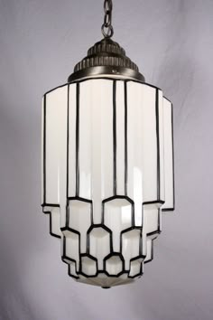 a light fixture hanging from a chain on a white wall with black and white trim