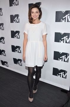 a woman in white dress and black tights posing for the camera at an event