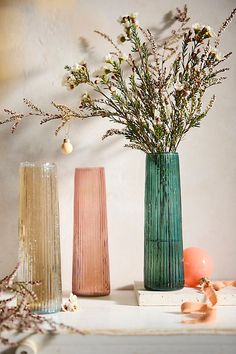 three vases with flowers in them sitting on a table next to an orange ball