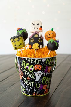 a bucket filled with halloween treats on top of a wooden table